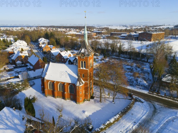 Snowy church with high tower surrounded by snow-covered trees and buildings, aerial view, Trinity