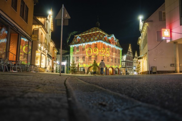 A lively cityscape at night with a brightly lit historic building and modest street lighting,