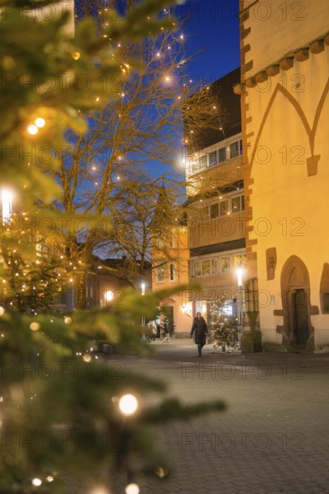 A Christmassy street with a single walker in front of historic buildings at dusk, Nagold, Calw