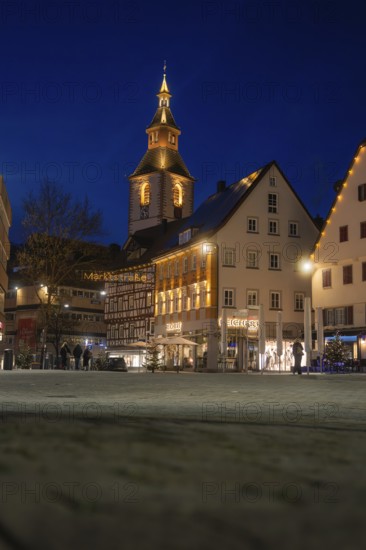 View of illuminated church tower and historic buildings in the evening darkness of the city,