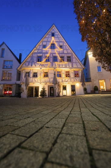 Half-timbered house with Christmas tree-shaped fairy lights against evening sky, Nagold, Calw