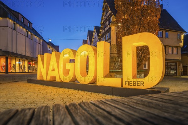 Large illuminated lettering 'Nagold' in an evening city promenade, modern architecture, Nagold,