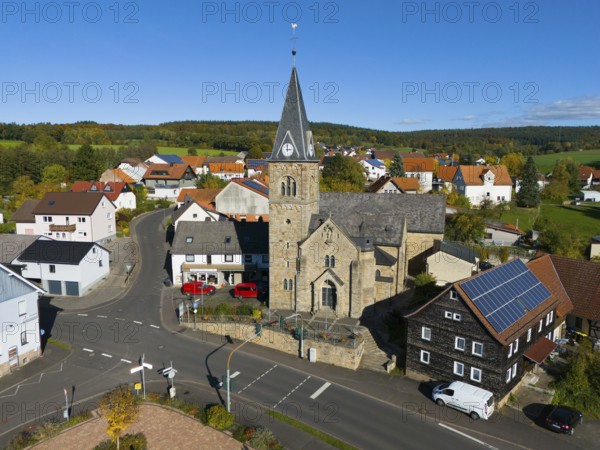 Close-up of a church in a village surrounded by roads and modern houses, aerial view,