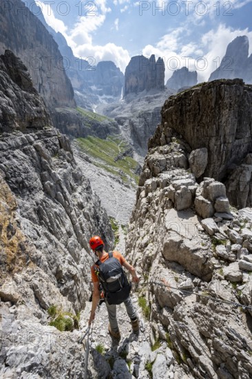 Mountaineers on a via ferrata in front of a picturesque mountain landscape with rocky peaks, Via
