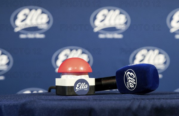 The microphone and a buzzer are on the table in front of the red button is pressed at 12:00 and
