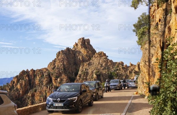 Bizarre rock erosion and car traffic, evening light, Calanche, Les Calanches de Piana,