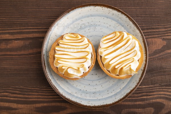 French lemon tart with meringue on brown wooden background, top view, flat lay, close up