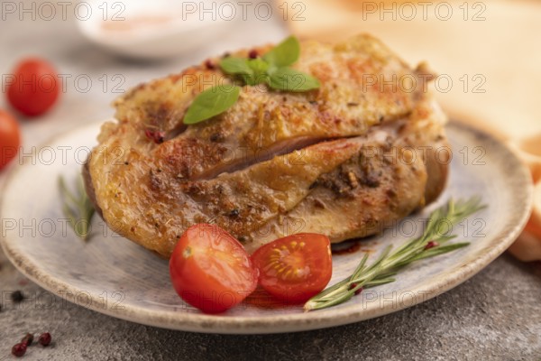 Fried Turkey Thigh with spices and rosemary on plate on brown concrete background and orange linen