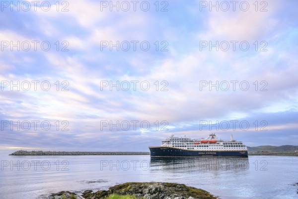 Cruise ship Havila Capella of Havila Kystruten competitor to Hurtigruten in Berlevag harbour, rocks