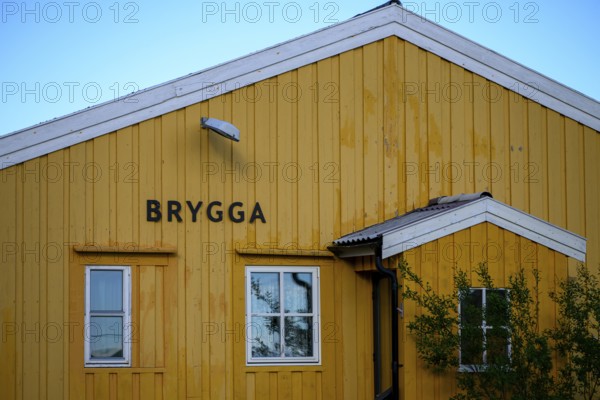 Yellow wooden building with simple, clear architecture, A yellow wooden building with two windows