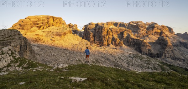 Mountaineer enjoying the view of rocky mountain peaks of the Brenta Mountains at sunset,
