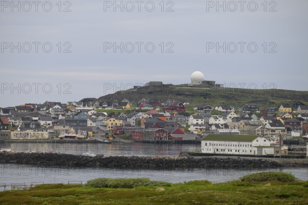 View of the port city of Vardø with large NATO radar systems on a hill in the background, Vardö,