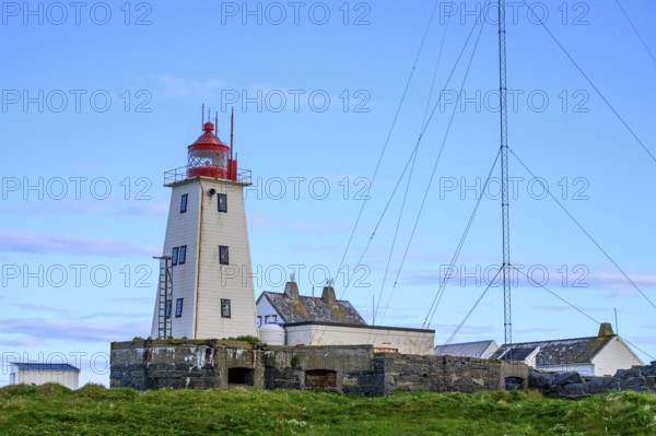 White lighthouse with red tip and antennas on the bird island of Hornoya, surrounded by grassy