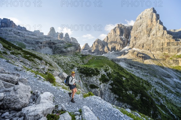 Female mountaineer hiking on a hiking trail in front of picturesque mountain scenery in the
