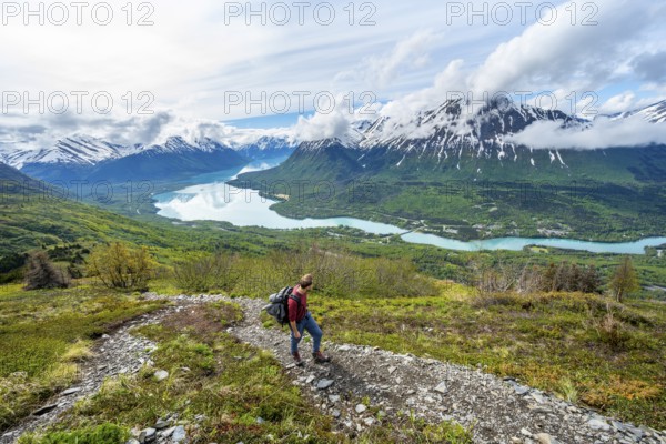 Climbers on a hiking trail, Slaughter Ridge Trail, view of snowy mountains and turquoise lake Kenai
