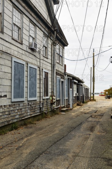 Alley leading to the ocean, weathered timber houses, traditional wood paneling, power lines, former