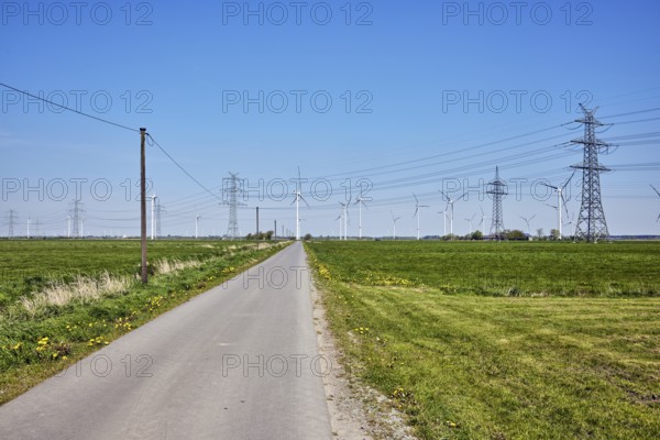 Wind turbines, power pole, overhead line, high-voltage pole, high-voltage line, road, meadows, blue