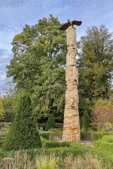 Tree trunk with carvings like a totem pole, stylized eagle on top in front of Schellenberg hunting