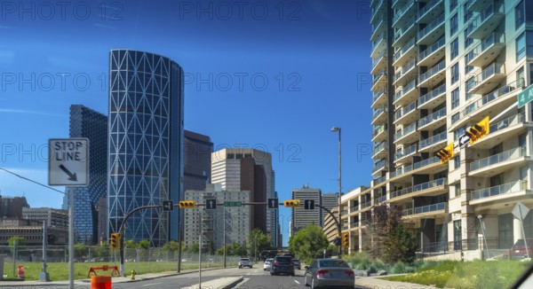 Cars driving on a multi lane road with the bow skyscraper and other modern buildings along the