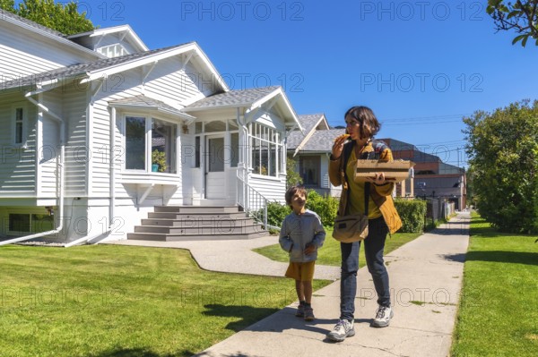 Mother and son are walking down a sidewalk in a residential neighborhood in calgary, alberta,