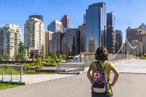 Young female tourist with a backpack is enjoying the cityscape of calgary, alberta, canada,