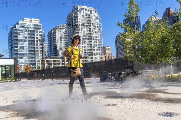 Female tourist walking in a foggy square in calgary city center during a sunny summer day, enjoying
