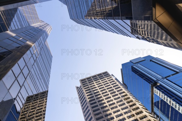 Low angle view of modern skyscrapers towering against a clear blue sky in calgary, alberta,