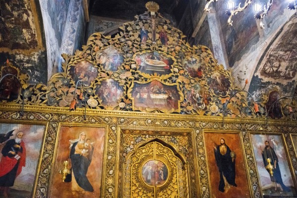 Artistically decorated icon wall with golden elements and religious representations in a church,