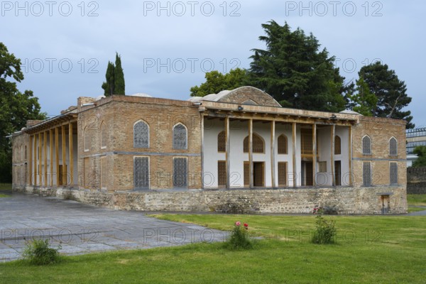 Old building with impressive brick walls and elegant columned entrance in garden surroundings,