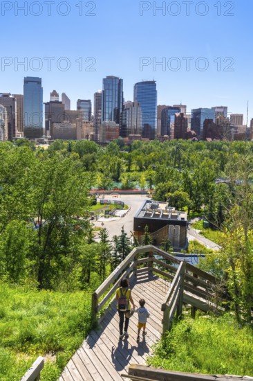 Mother and son walking down wooden stairs in a park, enjoying the view of the calgary skyline on a
