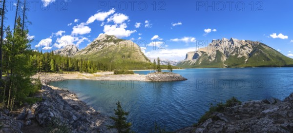 Sunlight illuminating the turquoise waters of lake minnewanka, reflecting surrounding mountains and
