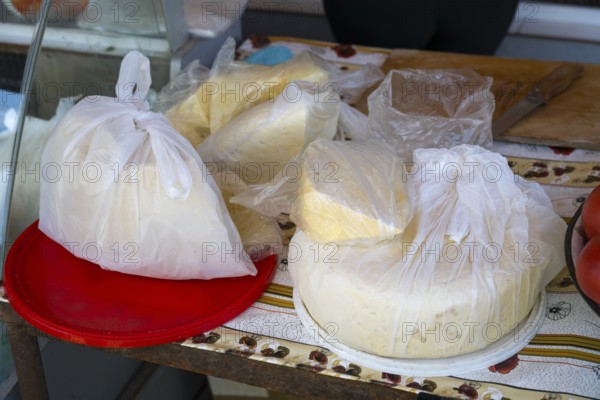 Different types of cheese in plastic packaging on a table at a market stall, selling cheese,