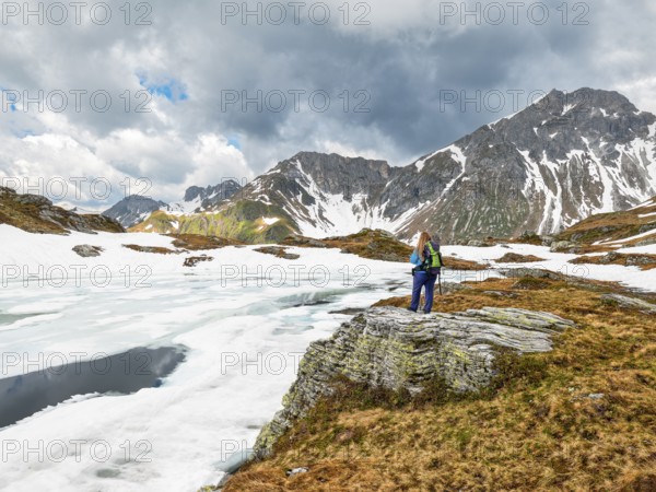 Half-frozen mountain lake with hiker, snow, Essersee, Stierkarkopf, Wildkarhöhe and Rothorn,