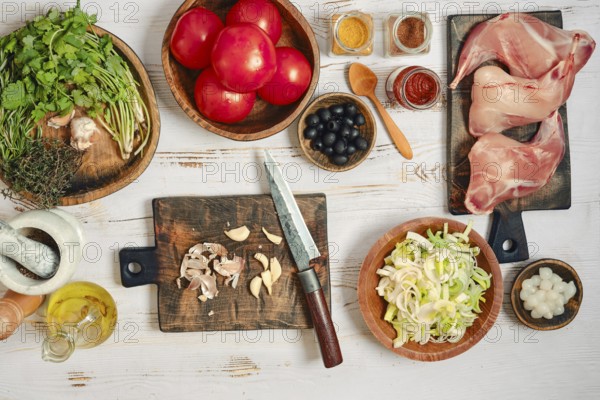 Fresh tomatoes, herbs, and spices are laid out on wooden boards in a kitchen. A knife and cutting