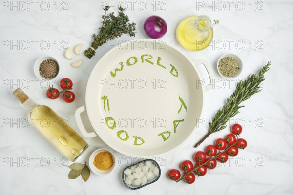 Fresh vegetables, herbs, white wine and cooking oil are arranged on a kitchen countertop next to an