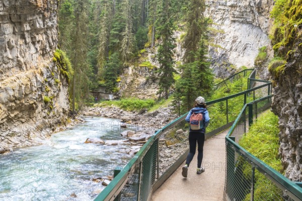 Female tourist with a backpack walking along a metal catwalk, taking in the scenic views of