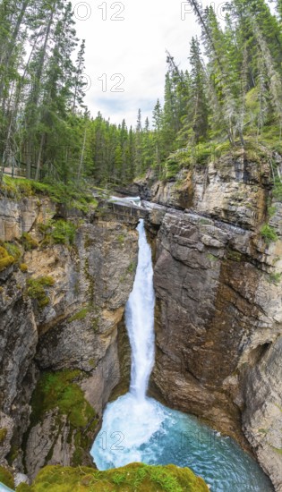 Breathtaking waterfall cascading into a vibrant turquoise pool amid the rugged beauty of johnston