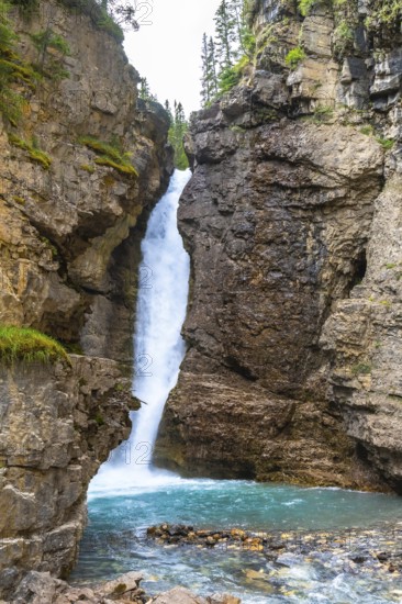 Breathtaking waterfall cascading into a vibrant turquoise pool, surrounded by rugged cliffs and
