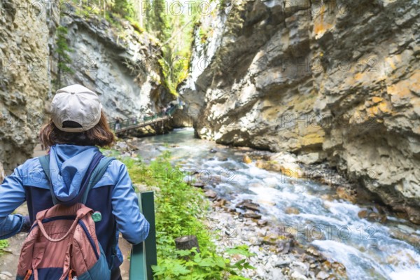 Female tourist with a backpack admiring the turquoise waters of bow river flowing through johnston