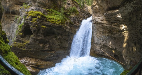Sunlight illuminating the vibrant turquoise pool at the base of a cascading waterfall in johnston