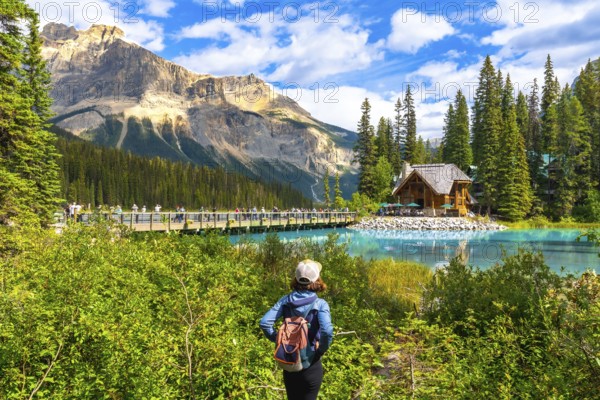 Female tourist with a backpack admiring breathtaking turquoise waters of emerald lake, featuring an