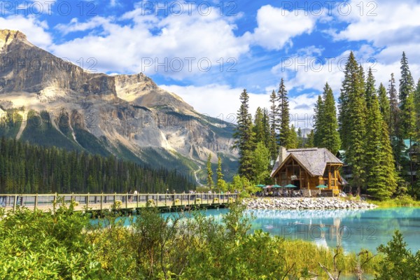 Wooden lodge sitting on the shore of a turquoise lake reflecting the surrounding lush vegetation