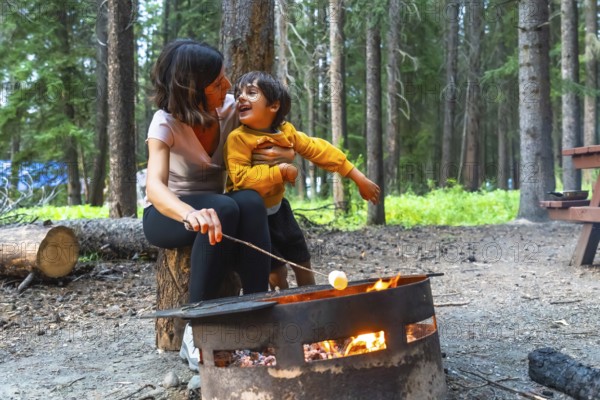 Mother and son are roasting marshmallows over a campfire in banff national park, alberta, canada,