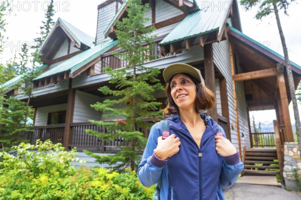 Female tourist wearing a baseball cap and backpack is arriving at emerald lake lodge in yoho