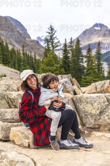 Mother and son sitting on rocks, soaking in the stunning views of turquoise peyto lake and