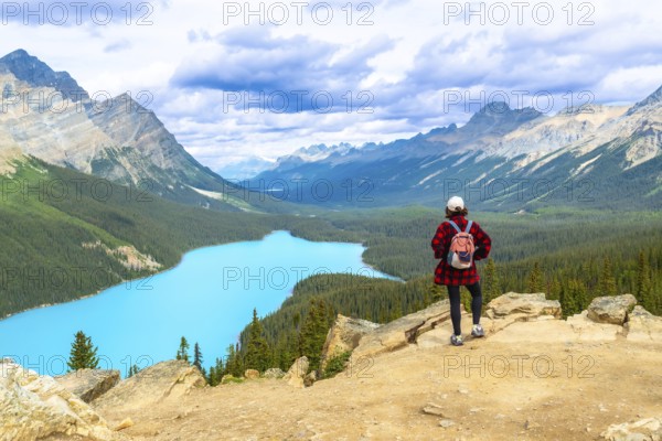 Hiker enjoying breathtaking view of turquoise peyto lake and surrounding rocky mountains in banff