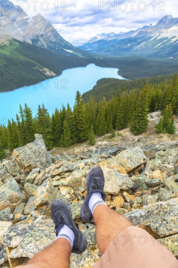Hiker resting on rocky terrain while enjoying breathtaking views of turquoise peyto lake,