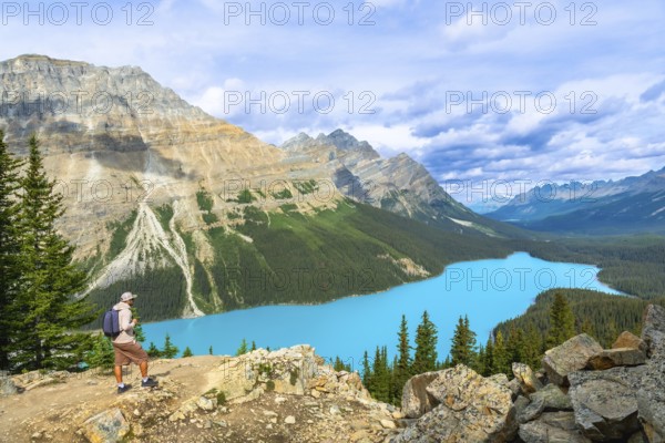 Hiker standing on a rocky outcrop, absorbing the breathtaking view of peyto lake's vibrant