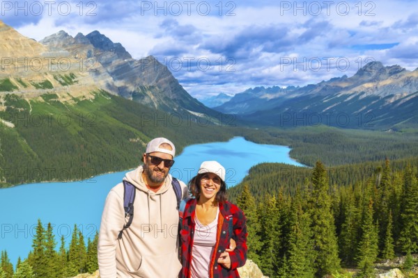 Two hikers enjoying the breathtaking panoramic view of turquoise peyto lake, surrounded by the