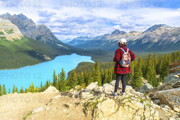 Female tourist with backpack standing on a rocky cliff overlooking the stunning turquoise waters of